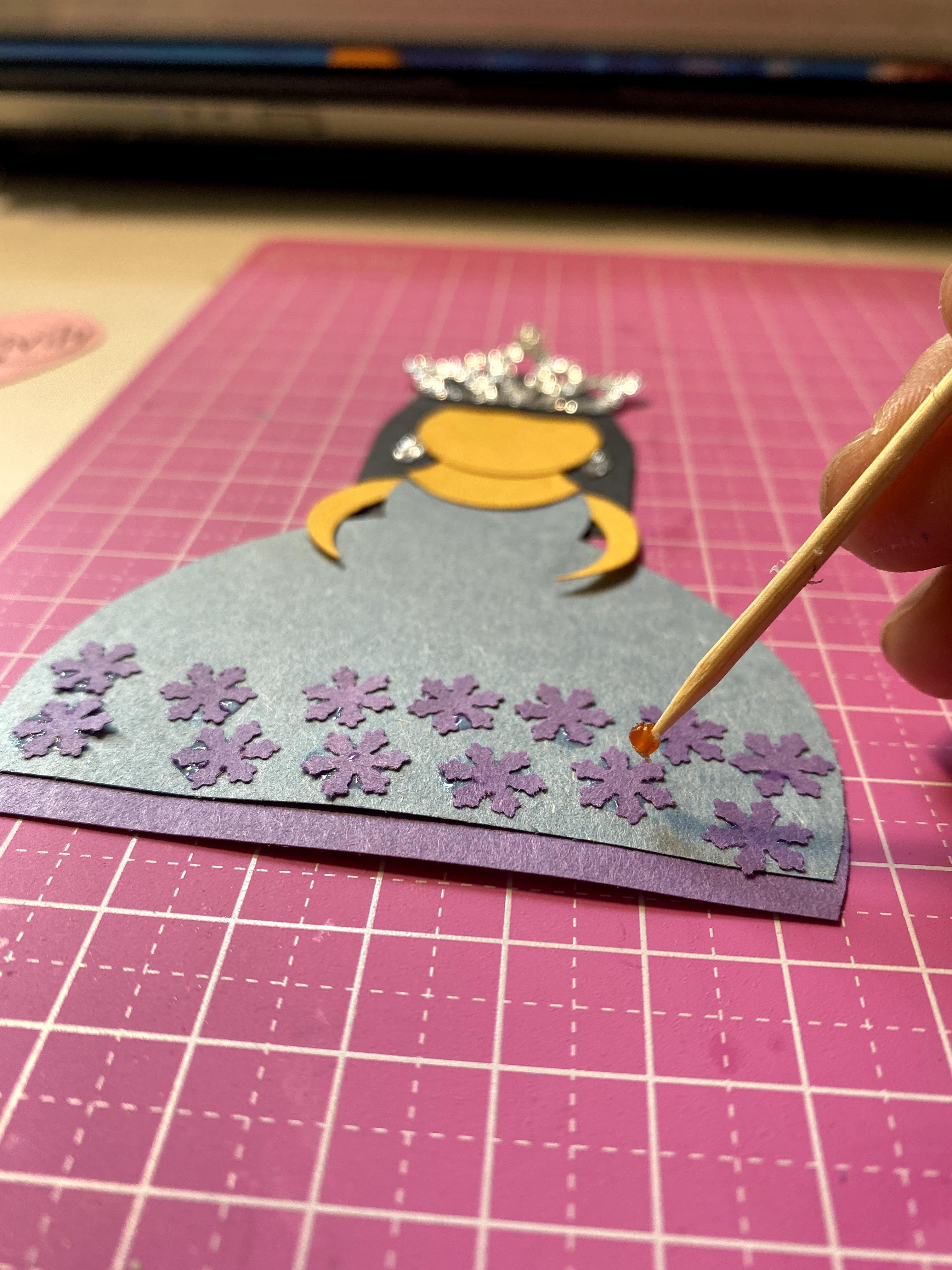 Adding small snowflake paper punches to decorate the paper princess dress.