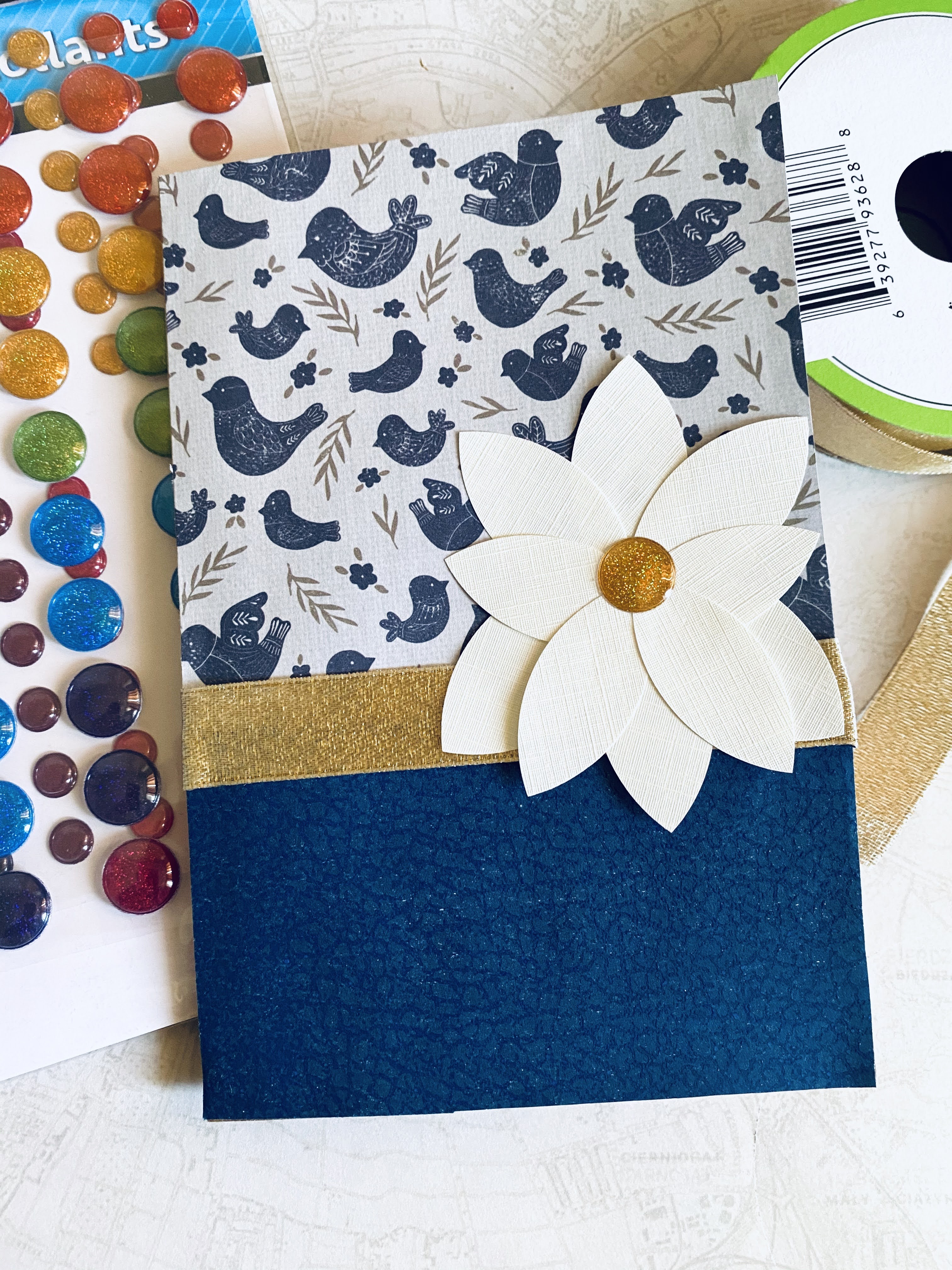 Navy and off-white card with magnolia flower and gold ribbon.  Patterned paper with navy blue birds.